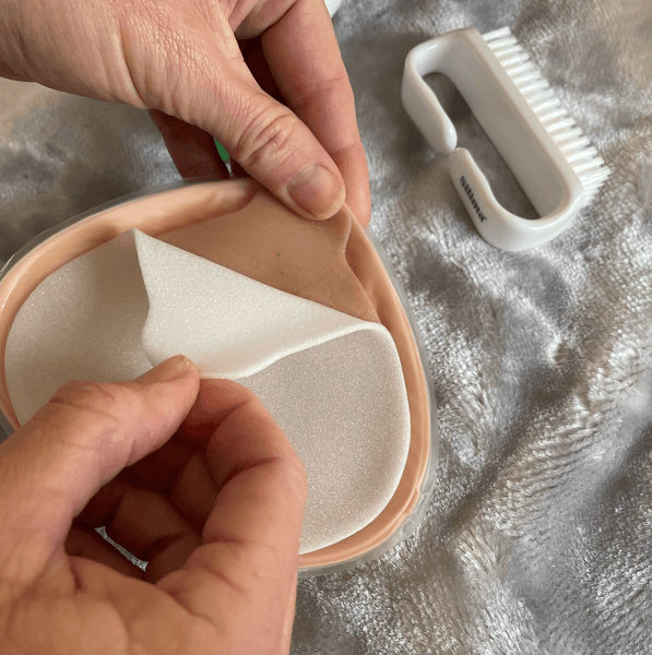 Peel adhesive backing from a lightweight silicone breast prosthesis, showcasing its secure fit and easy-to-clean design.