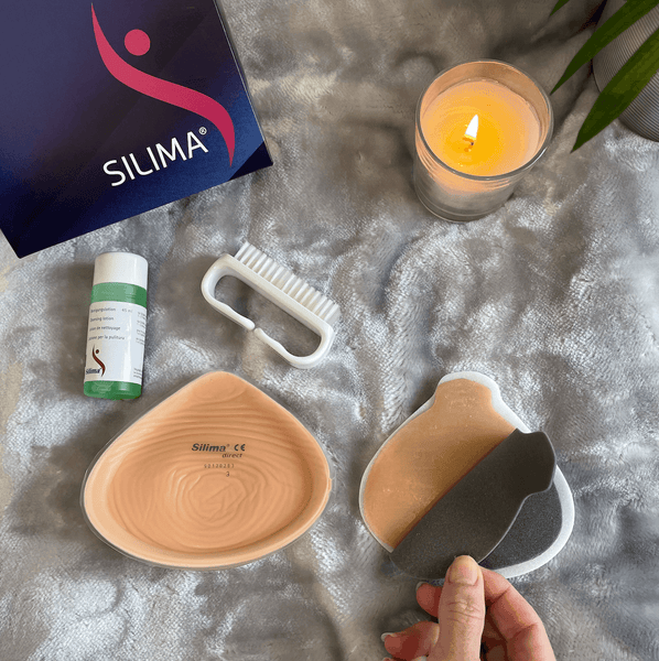 Direct Breast Form prosthesis with silicone material, adhesive option, and cleaning accessories. Includes a brush, cleaning solution, and packaging. Ideal for mastectomy support.
